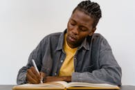 Person with Dreadlocks Writing on a Notebook