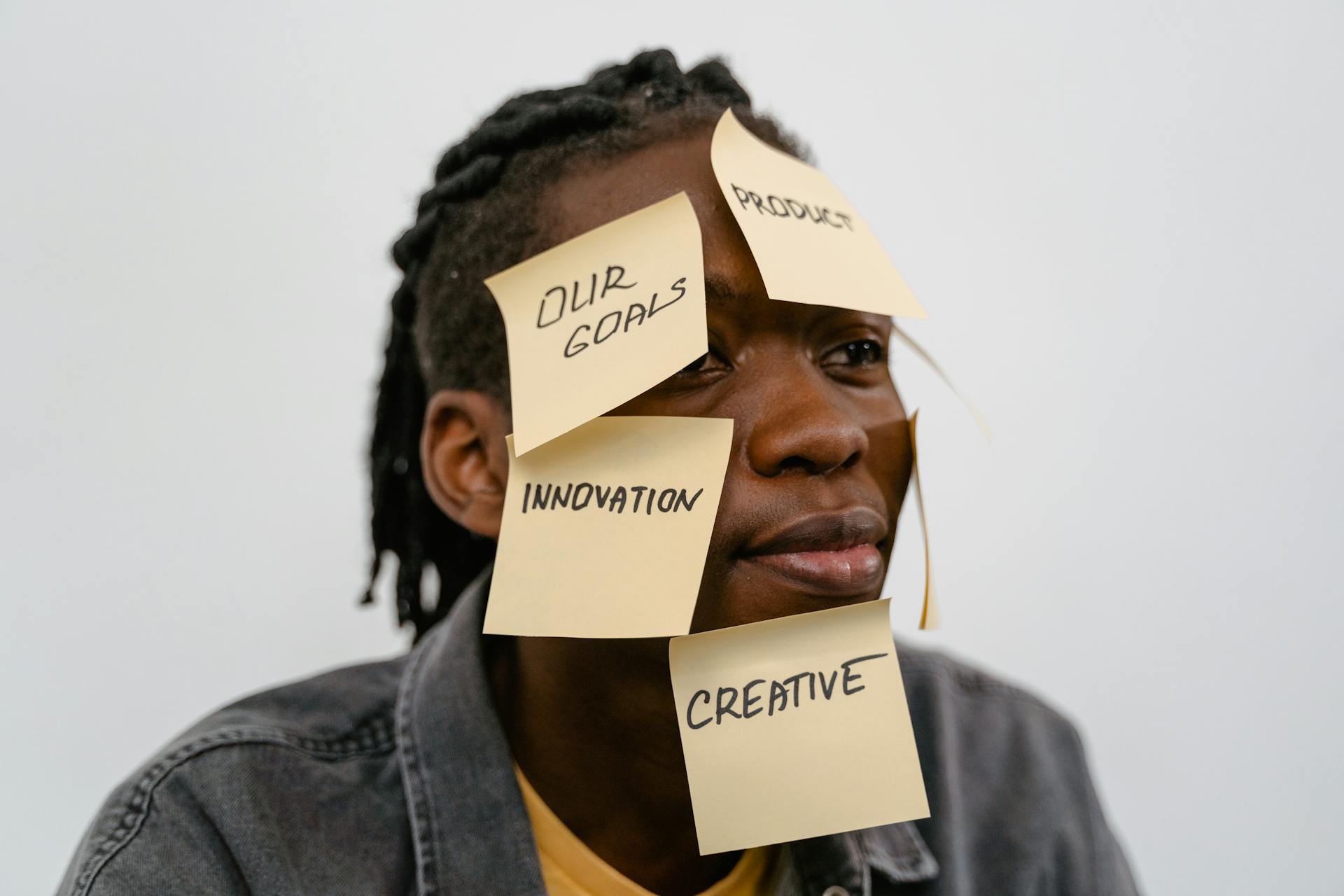 A creative adult with sticky notes displaying innovation concepts on their face.