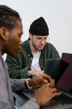 Two diverse men working on laptops in a modern office setting.