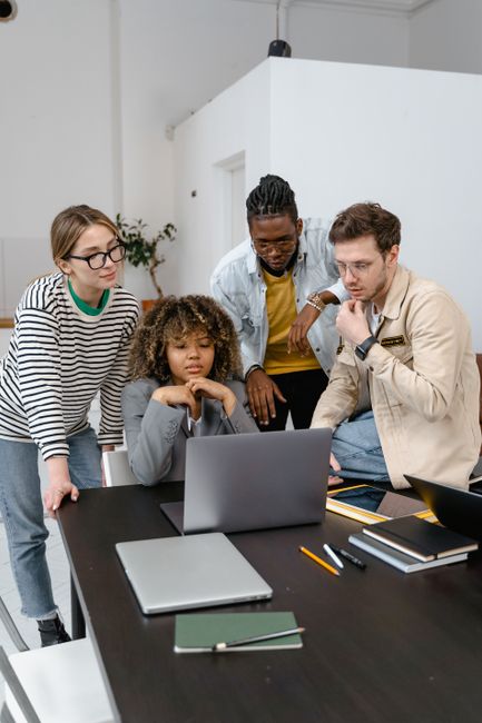 A diverse team collaborating around laptops in a modern office