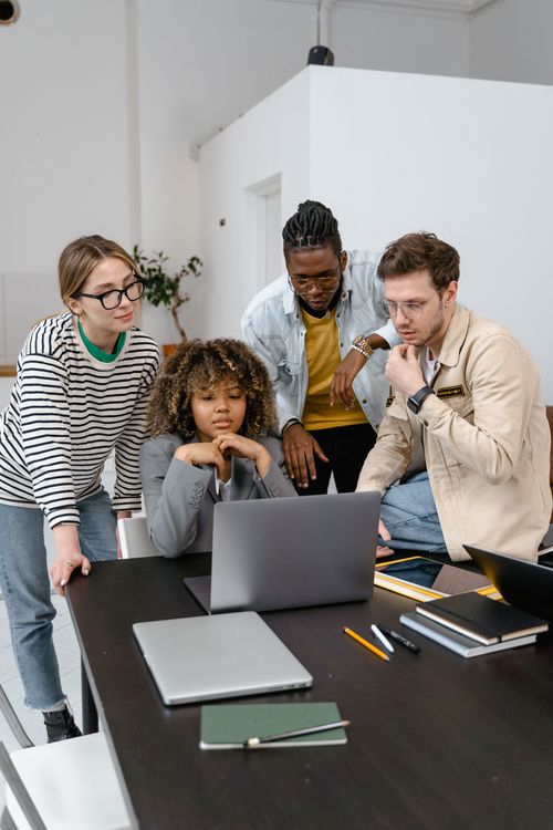 Startup team planning customer acquisition and digital marketing around a laptop
