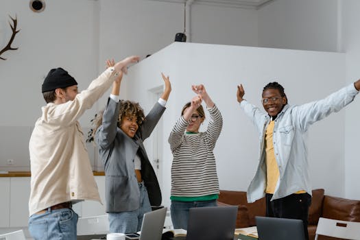 Diverse team celebrates success with enthusiasm in a modern office setting.