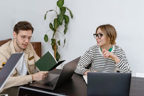 A Woman in Stripes Shirt Having a Meeting with a Man Holding a Notebook