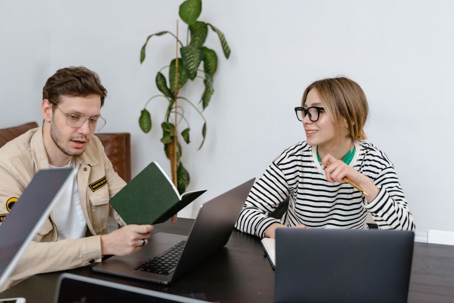 Two colleagues talking across a wooden table, photo by MART PRODUCTION on Pexels
