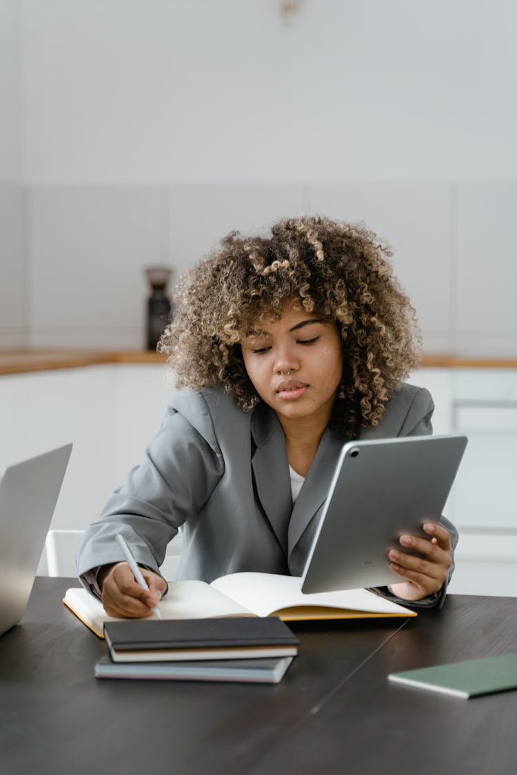 Woman Writing While Holding An Ipad 