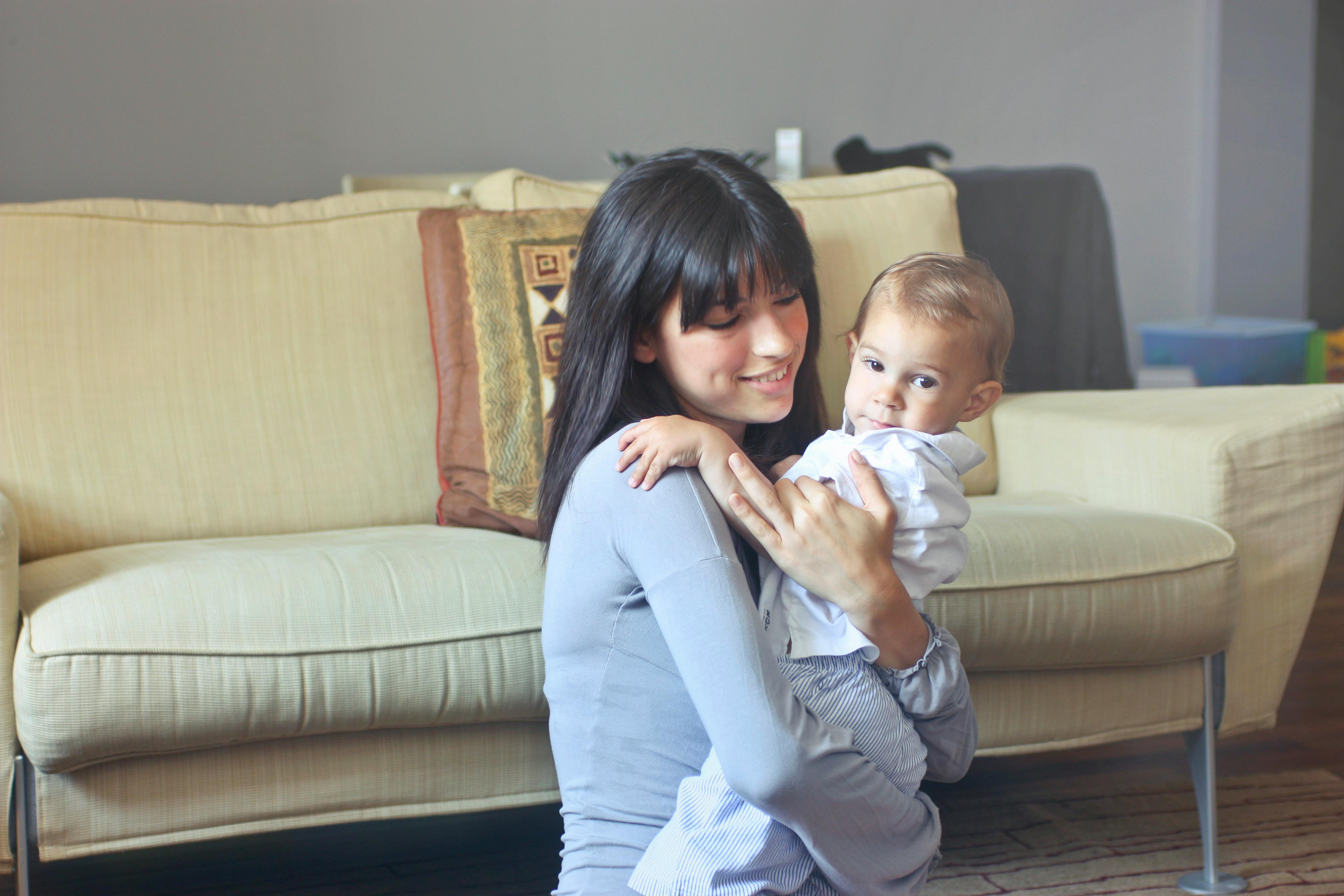 woman in gray sweater carrying toddler in white button up shirt