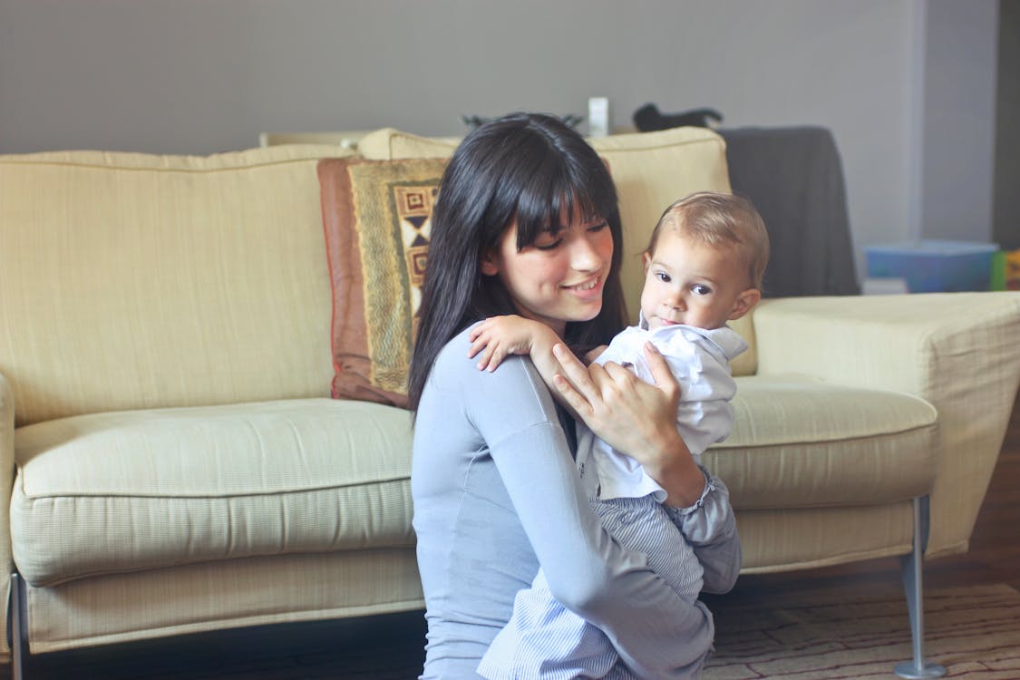 Free Woman in Gray Sweater Carrying Toddler in White Button-up Shirt Stock Photo