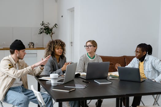 Group of diverse colleagues collaborating with laptops in a modern office setting.