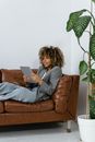 Woman in Black Blazer Sitting on Brown Sofa Chair Using Macbook