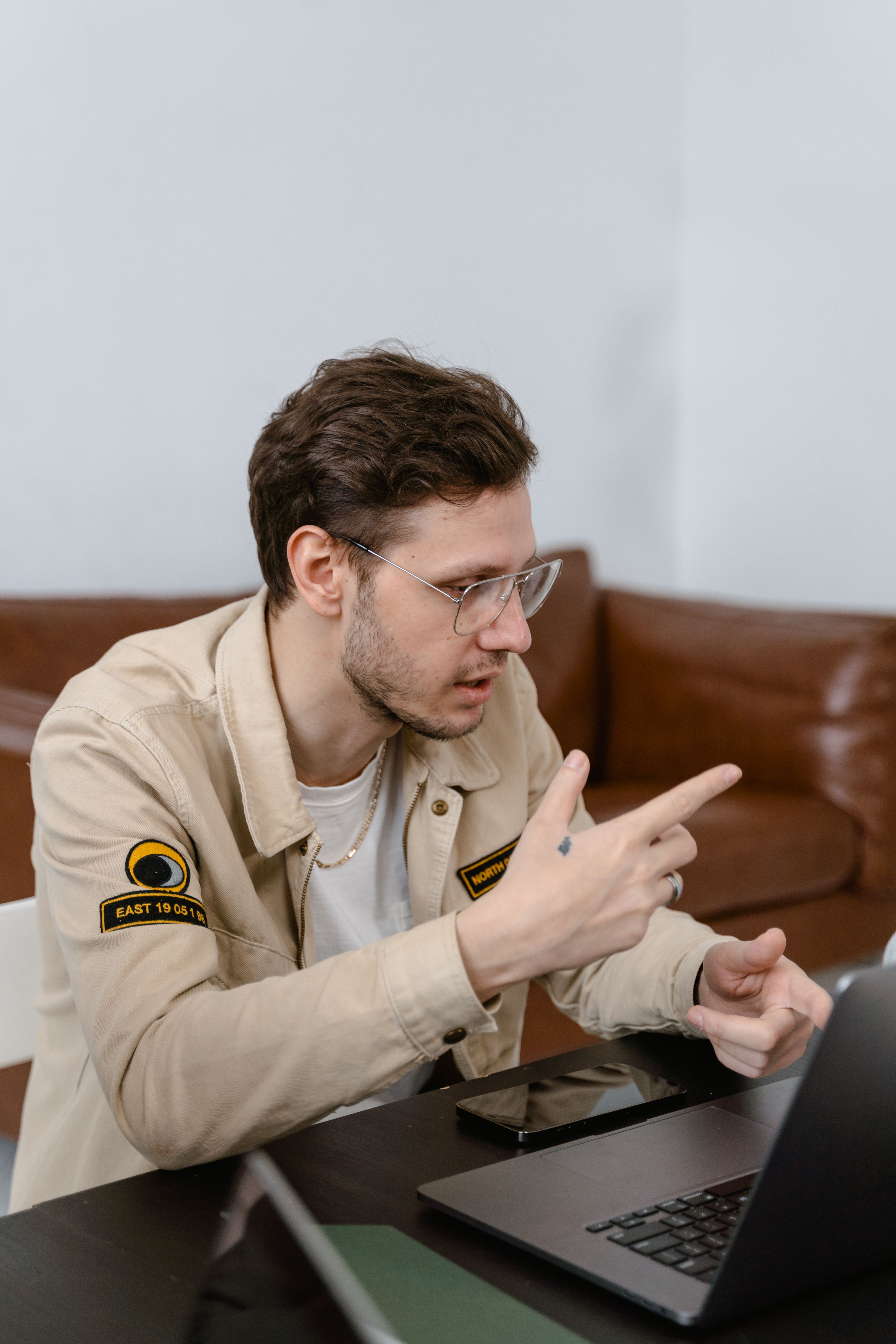A young man talking and gesturing while video conferencing on his laptop indoors.