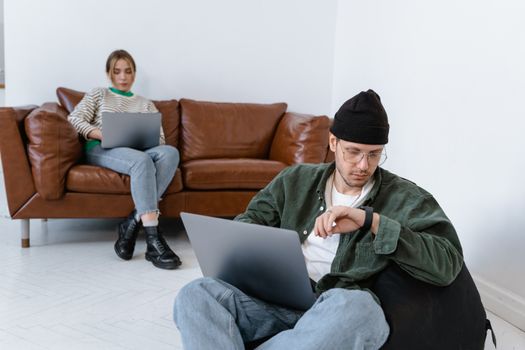 Two young professionals working on laptops in a cozy office setting, embodying modern entrepreneurship.