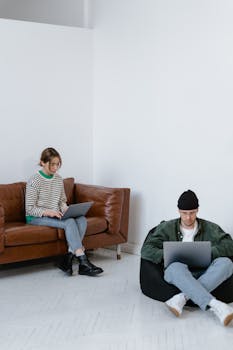 Two adults focused on laptops in a contemporary office setting, perfect for business themes.