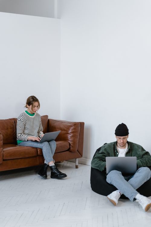 Free Two adults focused on laptops in a contemporary office setting, perfect for business themes. Stock Photo