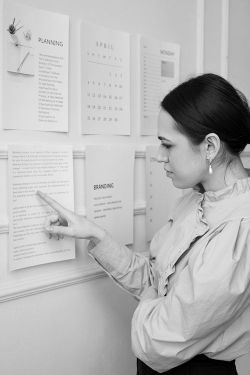 Free Focused young woman analyzes planning documents on the office wall. Stock Photo