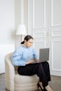Woman in Blue Dress Shirt Sitting on Gray Sofa Chair