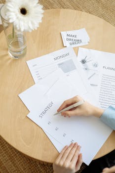 Overhead view of strategy planning papers on a round table with a person writing.
