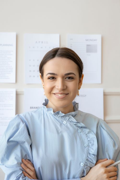 Free Smiling woman in light blue outfit posing confidently in a modern office setting. Stock Photo