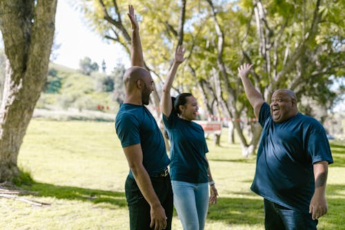 Group of People In Blue Crew Neck Shirts With Arms Raised