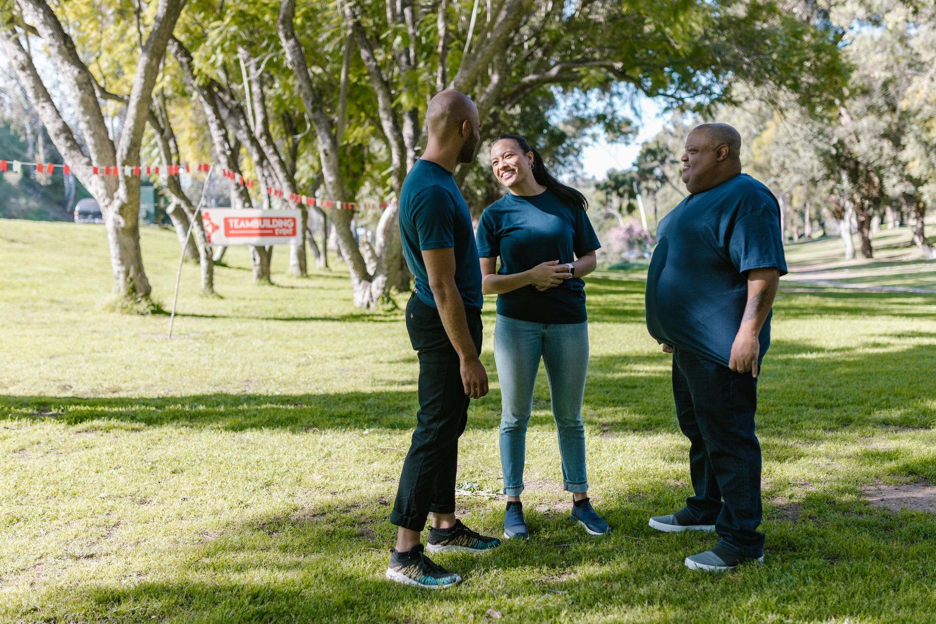 A diverse group enjoying a team building activity in a sunny park setting.