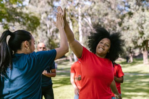 Free A diverse group celebrates with a high five during an outdoor team-building event. Stock Photo