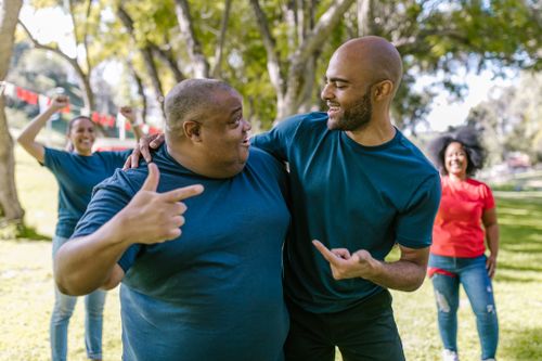 Free Cheerful friends engaged in a lively team-building exercise in a sunny park setting. Stock Photo