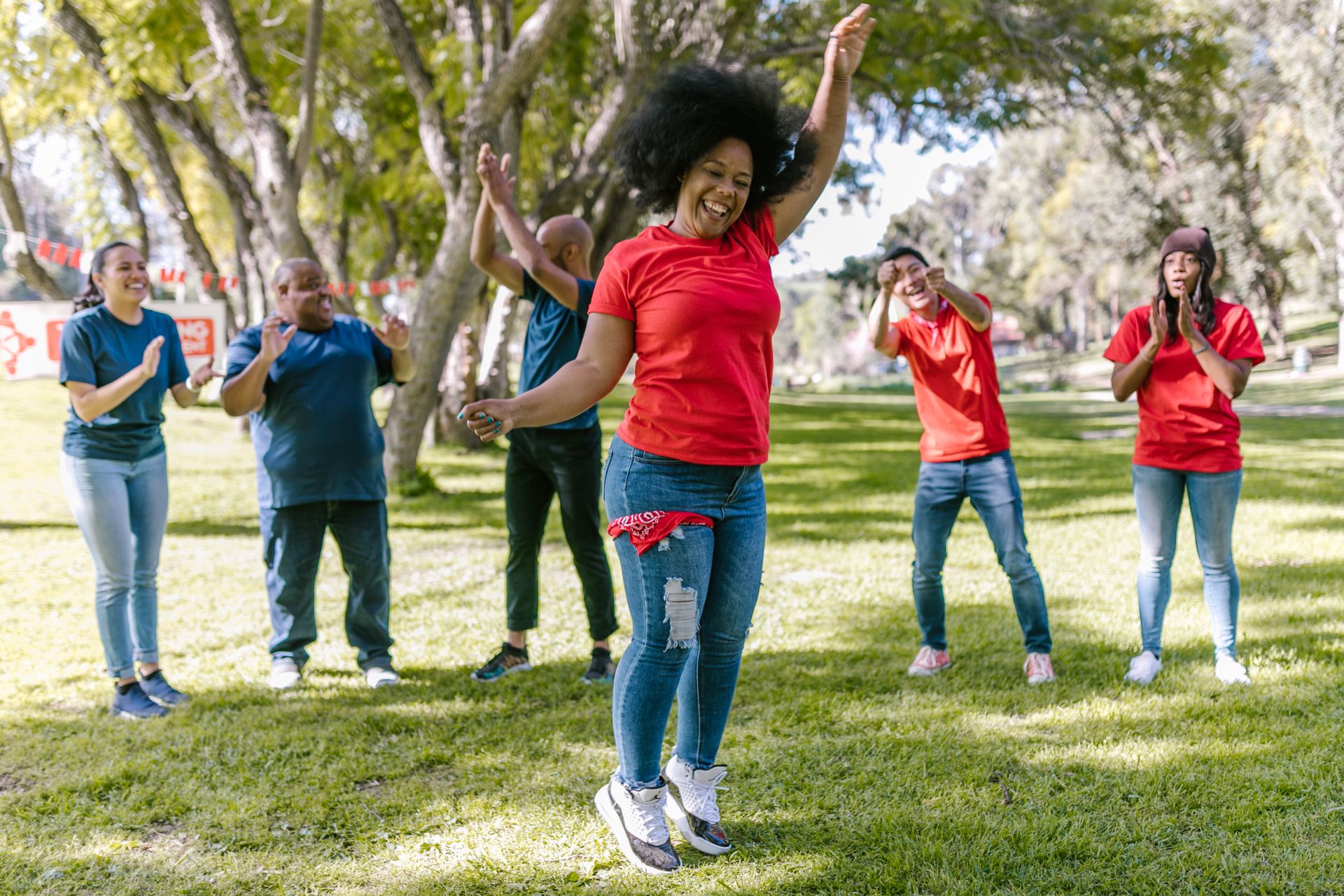 Diverse group of adults celebrating team spirit during an outdoor activity in a sunny park.