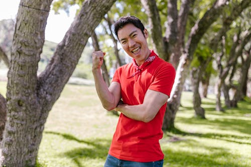 Smiling Man in Red Shirt Standing Near Tree