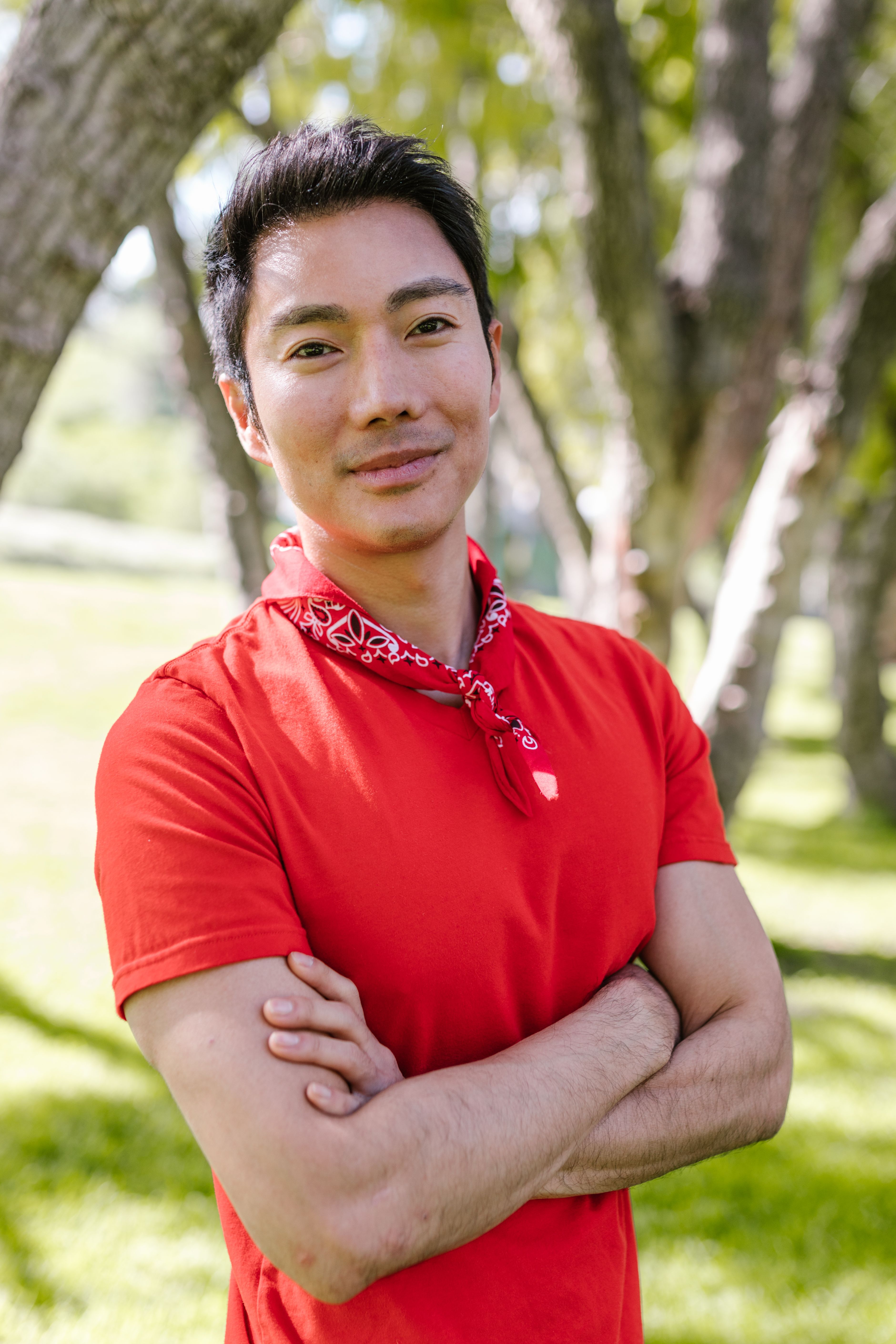 Portrait of a joyful man in a red shirt, enjoying a sunny day outdoors.