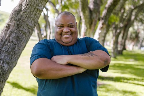 Free Portrait of a cheerful man enjoying a sunny day outdoors in a park. Stock Photo