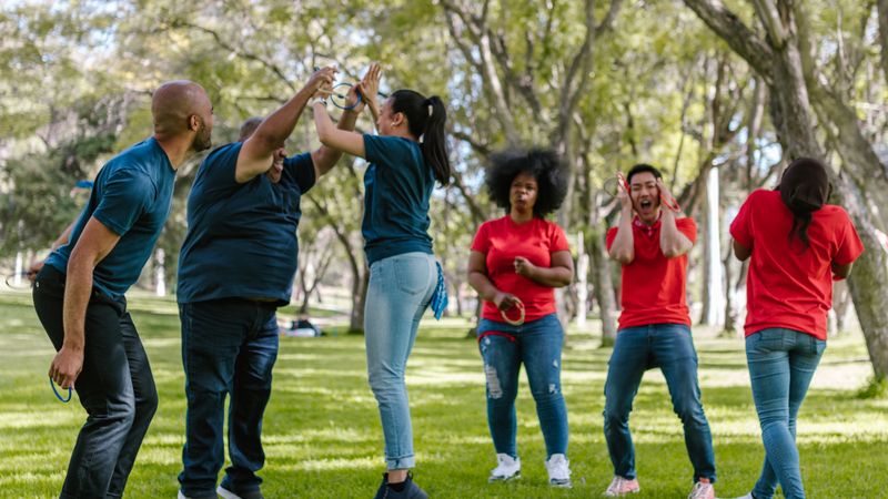 A diverse group of adults bond and have fun while participating in outdoor team building games.
