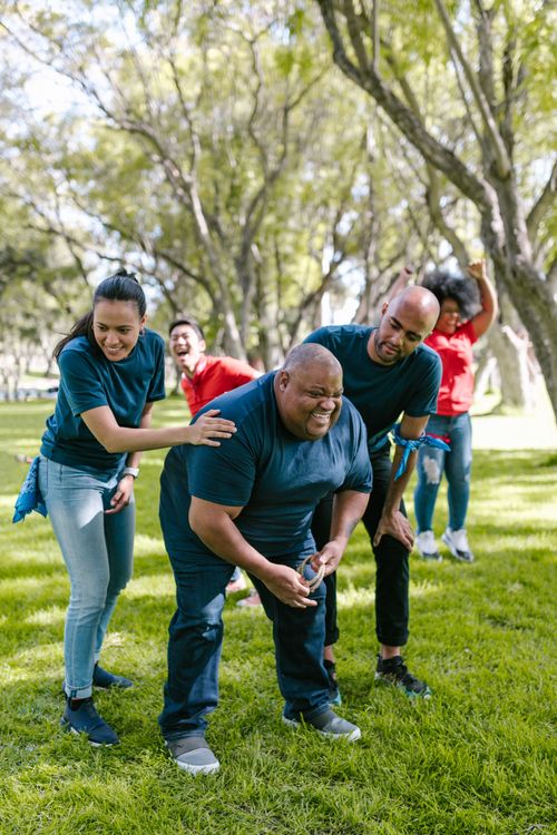 Free Group of adults enjoying a lively team building activity in a sunny park setting, promoting unity and fun. Stock Photo