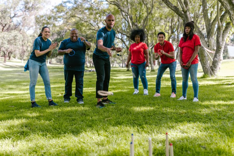 A diverse group enjoying a team building ring toss game outdoors in a sunny park