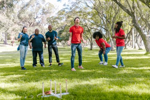 Free A multiracial group of adults enjoying a fun game of ring toss outdoors in a sunny park setting. Stock Photo