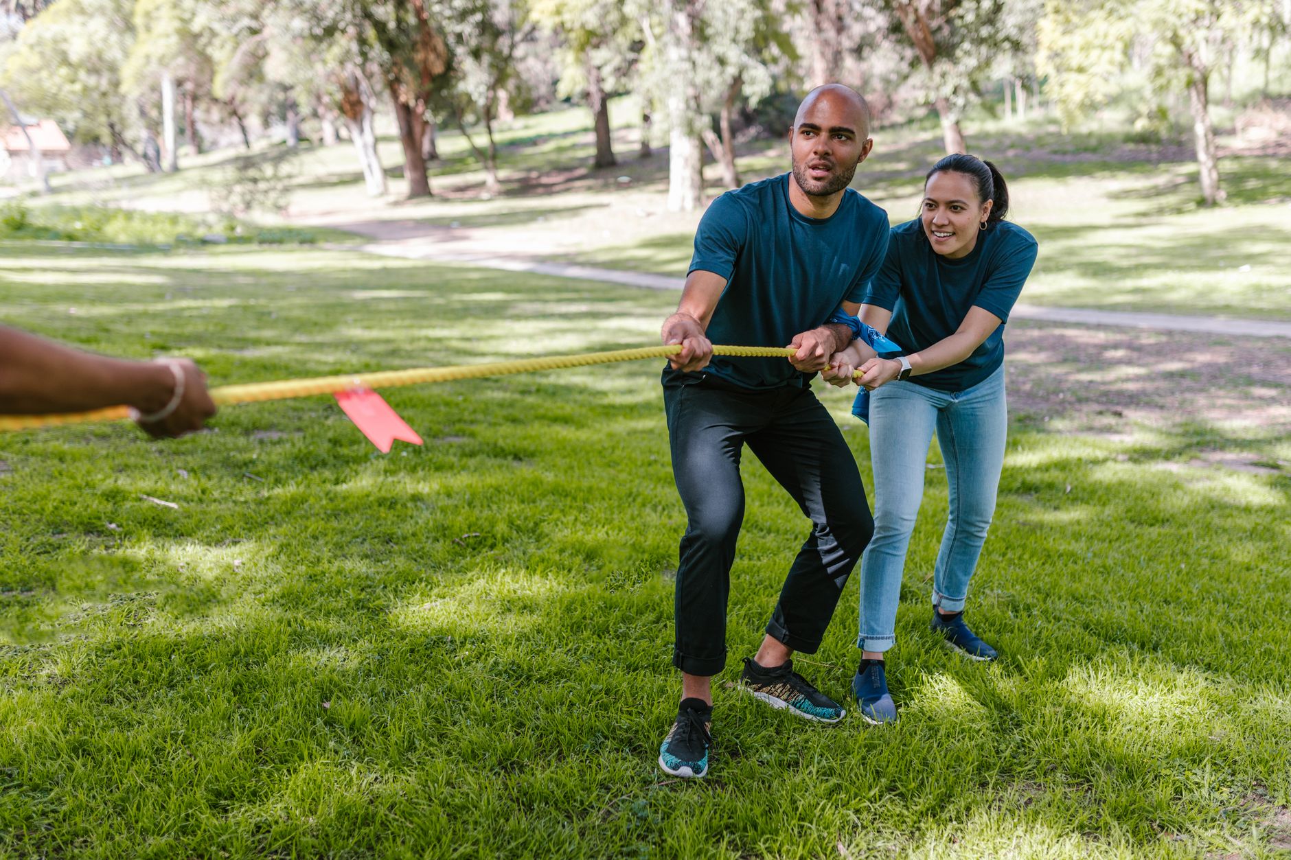 Two adults engaging in a tug of war during a team building event in a park.