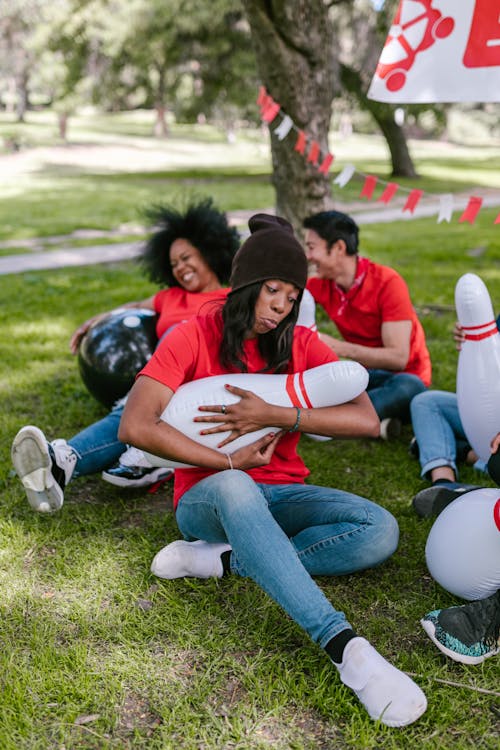 People Having Fun While Sitting On Green Grass