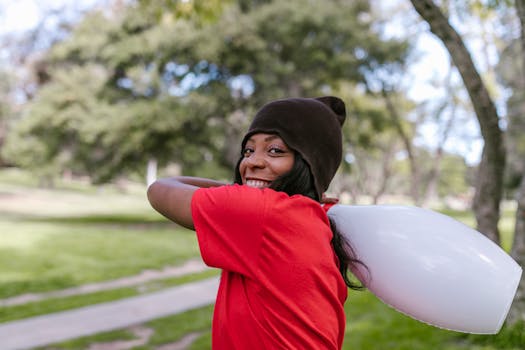 Smiling woman in a park holding a plastic toy, enjoying leisure time outdoors.