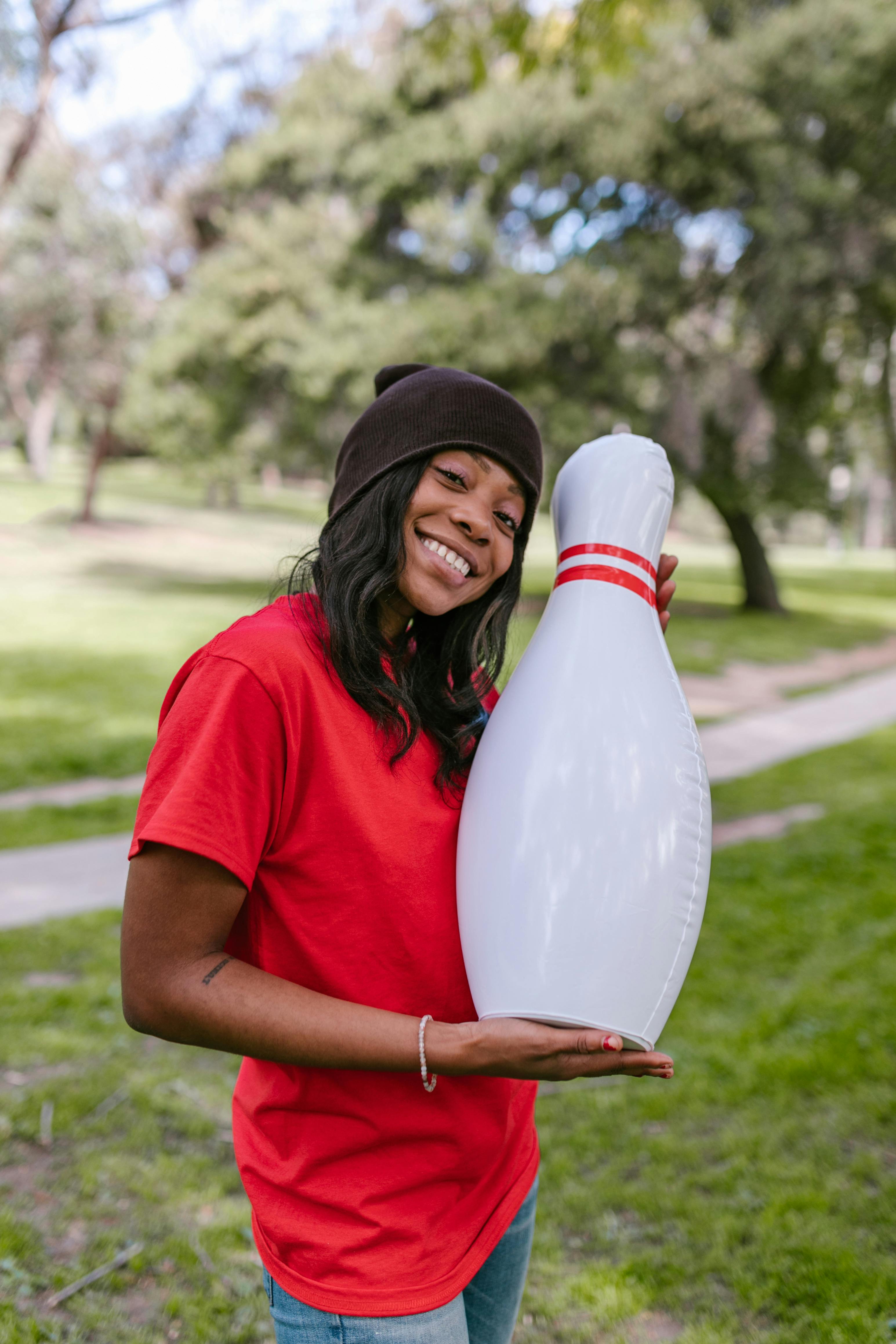 woman in red crew neck t shirt holding a plastic bowling pin