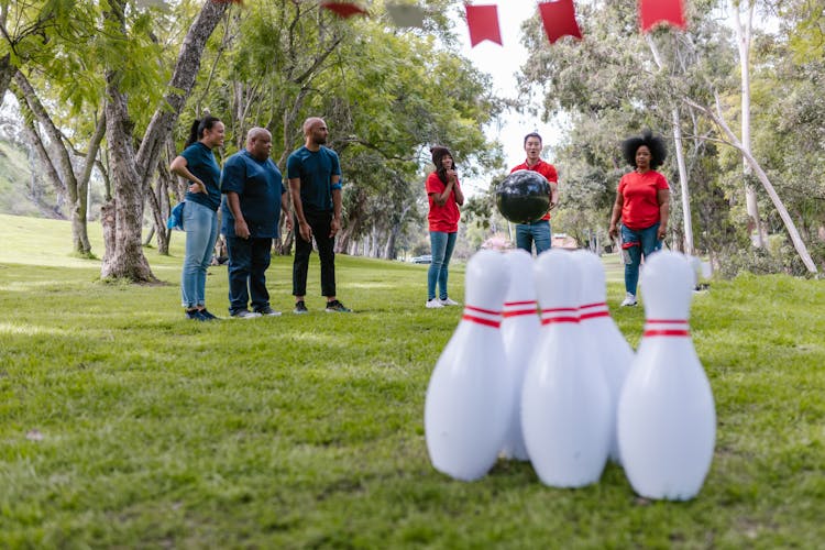 Group Of People Playing Bowling On Grass