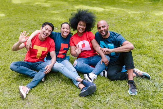 Four adults sitting on grass in colorful outfits, displaying teamwork and joy.
