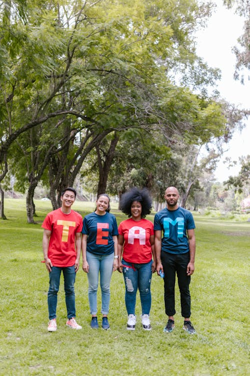 Group of People Standing on Green Grass Wearing Shirts Spelled Team
