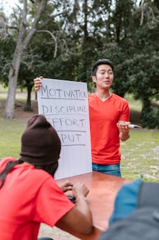A man leads a motivational session outdoor with a diverse group at a park.