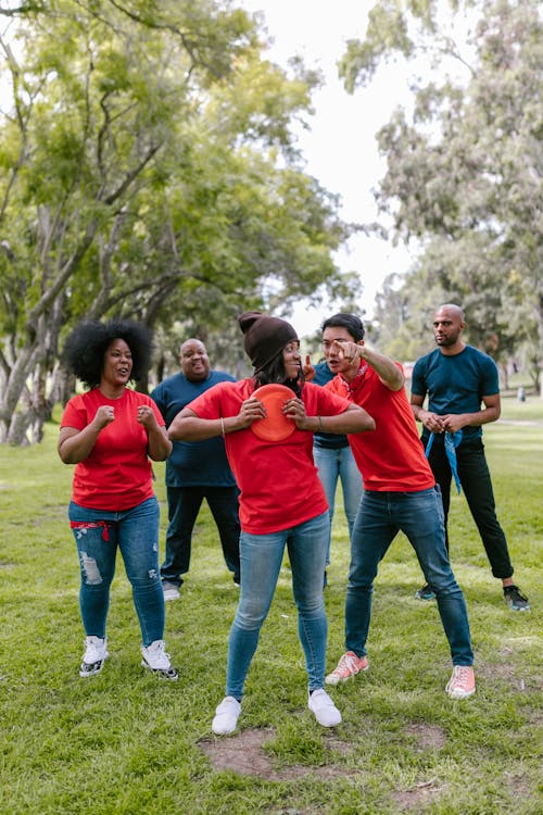 Free Group of adults enjoying a fun team-building exercise in a lush park setting. Stock Photo