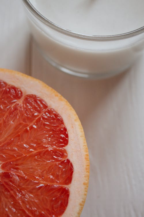 Slice of Grapefruit and a Glass of Milk on the Table