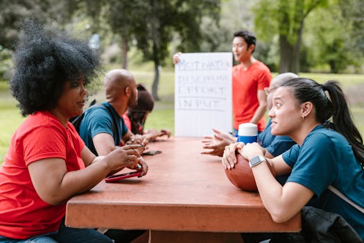 A diverse group of adults participate in an outdoor team-building meeting at a park.