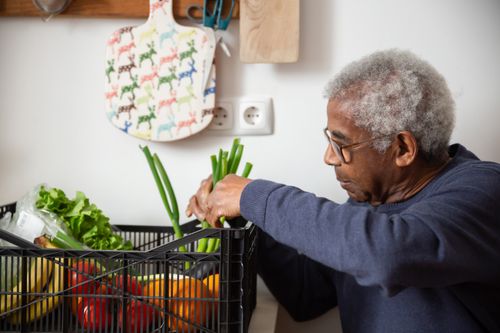Free Senior African American man organizing fresh vegetables indoors, showcasing healthy lifestyle. Stock Photo