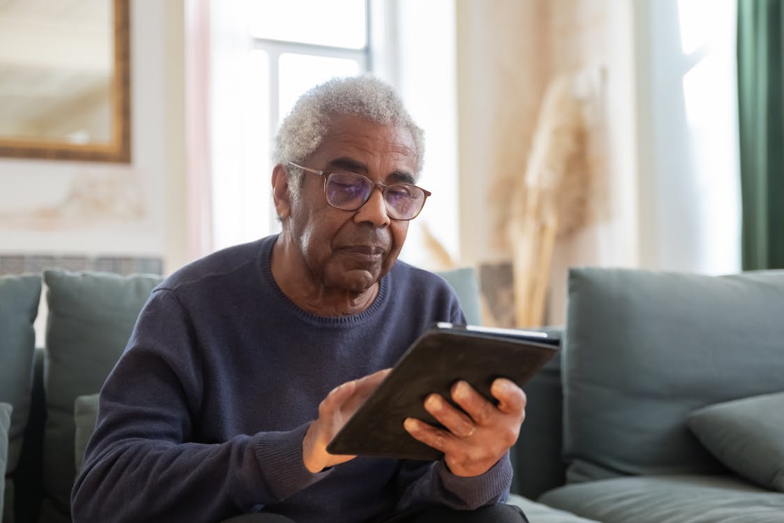Free An Elderly Man in Black Sweater Using a Digital Tablet Stock Photo