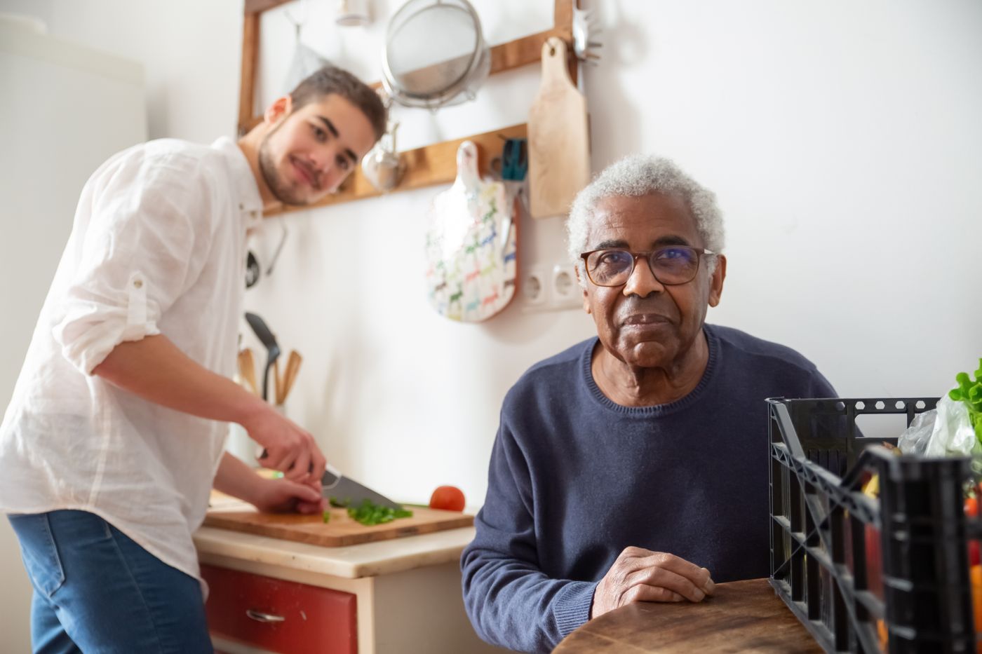 A senior man at home in his kitchen, sharing a warm moment with his caregiver
