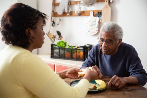 Free A woman assists an elderly man with meals at home, showcasing care and support. Stock Photo