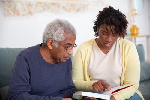 Free A Woman in Yellow Cardigan Talking to the Man while Reading a Book Stock Photo