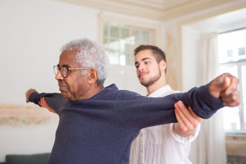 A Man in Blue Sweater Wearing Eyeglasses Doing Exercise